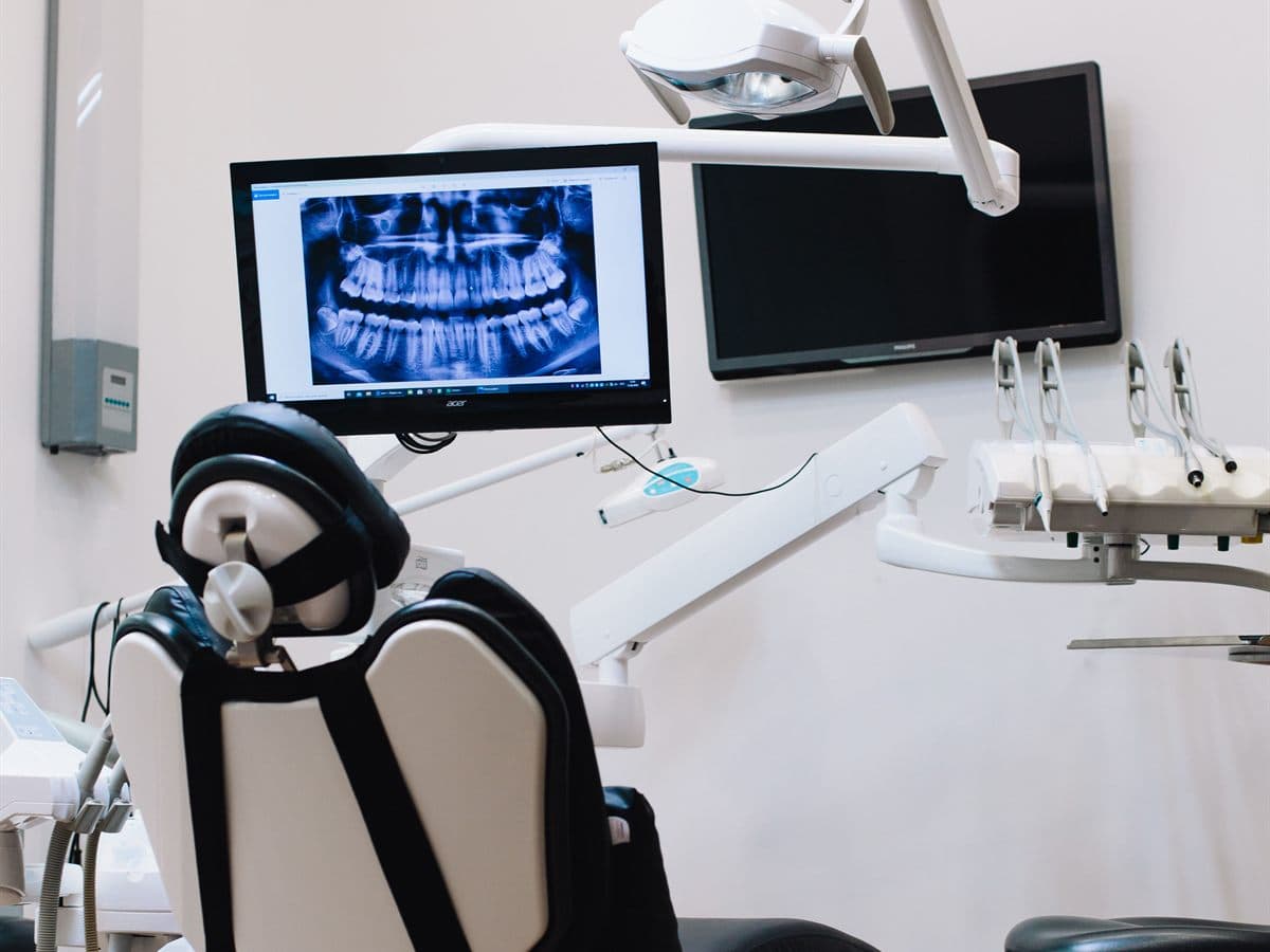 Gabinete dental con sillón, lámpara y una radiografía panorámica en la pantalla